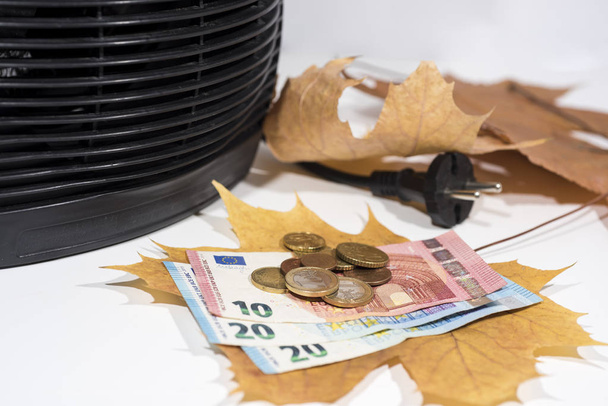 Geld für Heizkosten mit schwarzer Heizung auf weißem Hintergrund. Herbstzeit. - Foto, Bild