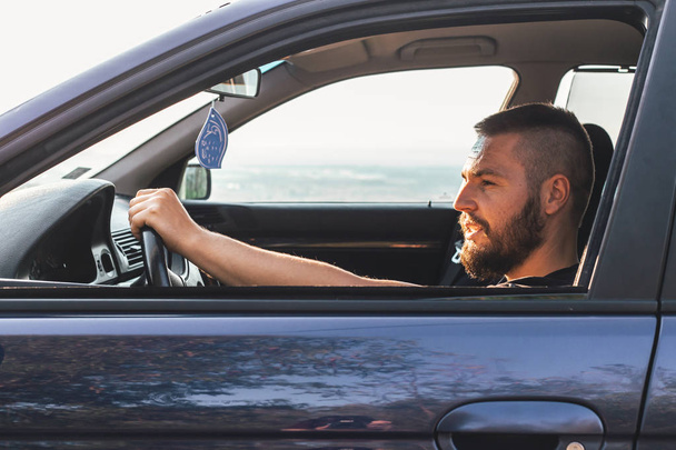 Cute, bearded man driving a car. Side window view. Transportation concept - Foto, afbeelding