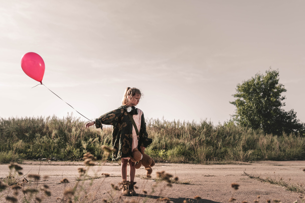 selective focus of cute kid with gas mask holding balloon, post apocalyptic concept - Photo, Image
