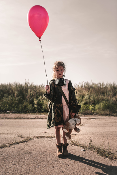 cute kid with gas mask holding red balloon, post apocalyptic concept - Photo, Image