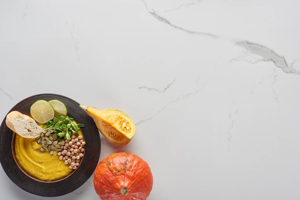 vue de dessus de la purée automnale de soupe de citrouille dans un bol près de la citrouille sur la surface du marbre
 - Photo, image