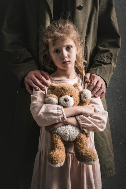 levágott kilátás férfi álló gyerek mellett Teddy mackó, poszt apokaliptikus koncepció - Fotó, kép