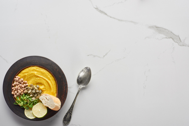 top view of autumnal mashed pumpkin soup on marble table with spoon - Foto, afbeelding