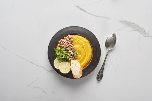 вид осеннего супа из тыквы на мраморном столе с ложкой
 - Фото, изображение