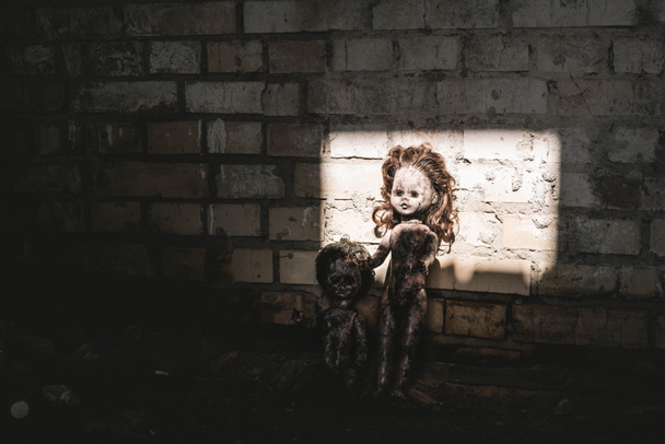 luz do sol em bonecas velhas e assustadoras perto da parede de tijolos, conceito pós-apocalíptico
 - Foto, Imagem