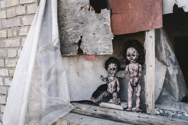 scary and burnt baby dolls near rusty window, post apocalyptic concept - Photo, Image