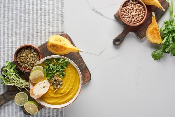 top view of autumnal mashed pumpkin soup on wooden cutting board on striped napkin - Zdjęcie, obraz