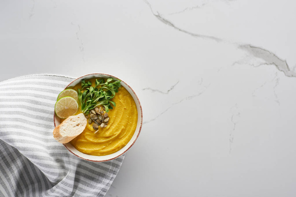 top view of tasty mashed pumpkin soup near striped napkin on marble surface - Foto, Imagem