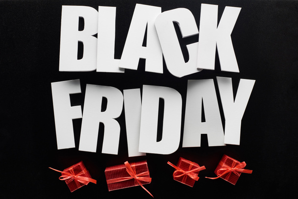 Draufsicht auf Black Friday Schriftzug und rote Geschenke isoliert auf Schwarz - Foto, Bild