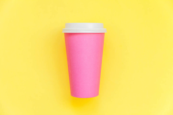 Gewoon plat lay design roze papieren koffie kopje geïsoleerd op gele kleurrijke trendy achtergrond - Foto, afbeelding