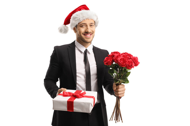 Young man in a suit and tie with a Santa Claus hat holding a bun - Foto, afbeelding