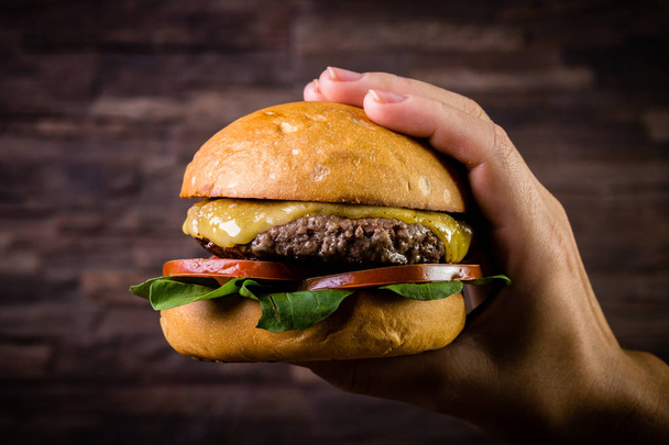 Рука держит бургер из говядины
 - Фото, изображение