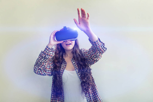 Sonríe mujer joven usando realidad virtual gafas VR casco auriculares sobre fondo blanco. Smartphone con gafas de realidad virtual
 - Foto, Imagen