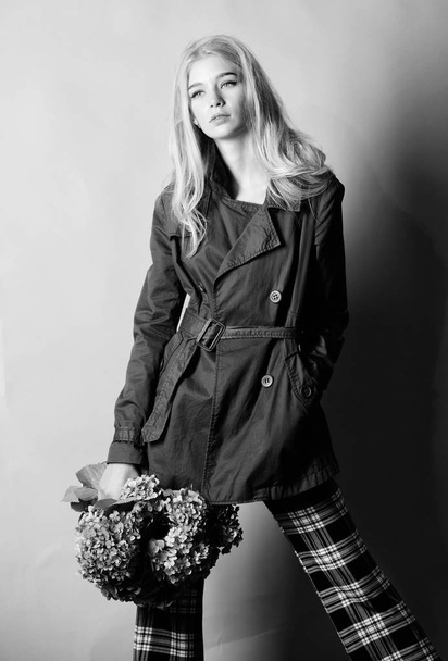 Must have concept. Woman blonde hair posing coat with flowers bouquet. Clothes and accessory. Girl fashion model wear coat for spring and autumn season. Trench coat fashion trend. Fashionable coat - Foto, immagini