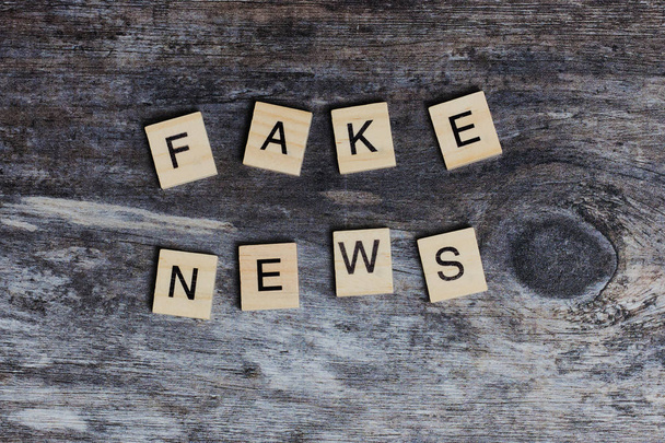 the English words - fake news - laid with wooden letters on wooden background - Foto, afbeelding