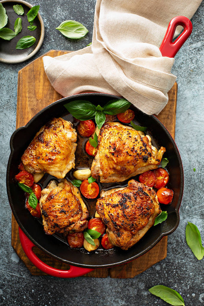 Chicken thighs roasted with tomatoes and garlic - Фото, изображение