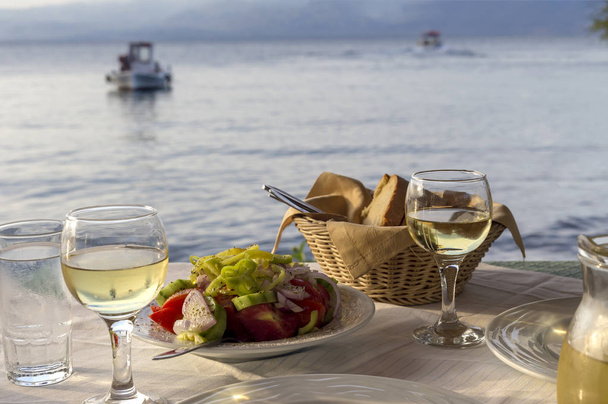 Salad and wine in a tavern near the sea - Photo, Image