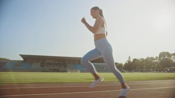 Beautiful Fitness Girl in Light Blue Athletic Top and Leggings Jogging in a Stadium. She is Running on a Warm Summer Afternoon. Athlete Doing Her Routine Sports Practice on a Track. Slow Motion. - Πλάνα, βίντεο