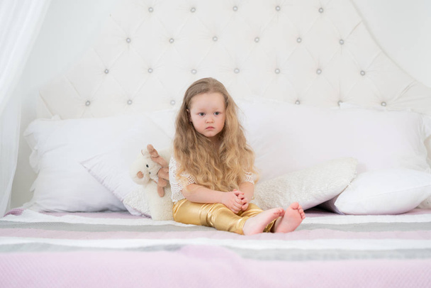 portrait of a sad girl with unhappy face sitting on a bed in the bedroom - Fotoğraf, Görsel
