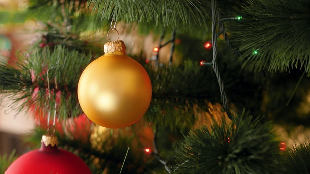 美しいカラフルなボールのスライダーと火の木の枝に輝くクリスマスライトから4kパンビデオ。あなたの冬の休日やお祝いのための完璧なショット - 映像、動画