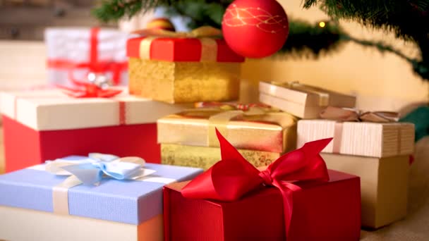 βίντεο 4K της κάμερας αργά κινείται προς μεγάλο σωρό των Χριστουγέννων δώρα και δώρα σε διακοσμημένα κουτιά με κορδέλα φιόγκο στο πάτωμα στο σαλόνι. Τέλεια βολή για τις χειμερινές σας διακοπές και γιορτές - Πλάνα, βίντεο
