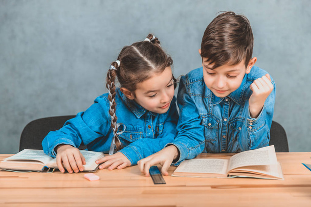 Smart boy and girl totally involved in the process of reading. Boy is pointing at something interesting in his book. - Φωτογραφία, εικόνα