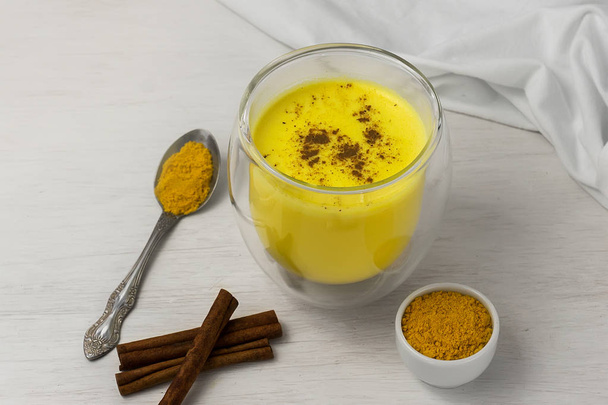 Traditional Indian drink. Golden latte, turmeric milk with spice on a white wooden background - Foto, Bild