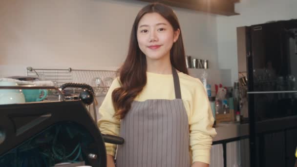 Ritratto giovane donna asiatica barista felice sorridente al caffè urbano. Piccolo imprenditore coreano ragazza in grembiule relax sorriso dentato guardando la fotocamera in piedi al bancone in caffetteria. - Filmati, video