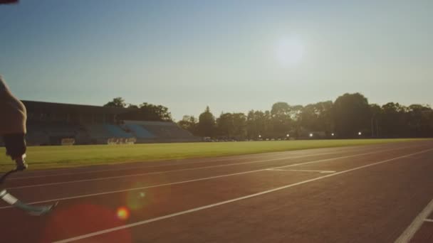 Athletic Disabled Fit Man with Prosthetic Running Blades is Training on a Outdoors Stadium on a Sunny Afternoon. Amputee Runner Jogging on a Stadium Track. Motivational Sports Footage. Tracking Shot. - Felvétel, videó