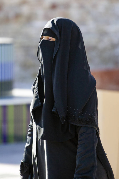 Der Niqab ist eine lange Tunika, die Körper und Kopf vollständig bedeckt. Kaum überlässt sie dem Überziehungskredit die Augen der Frau. - Foto, Bild