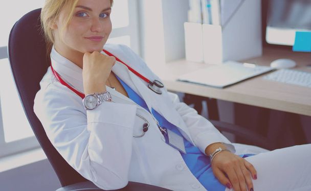 Portrait of young female doctor sitting at desk in hospital - Fotó, kép