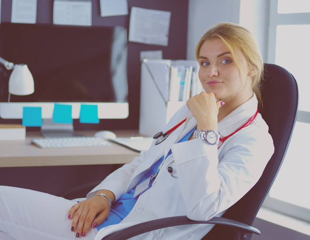 Portrait of young female doctor sitting at desk in hospital - Фото, зображення