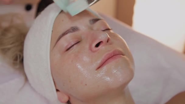 Professionele schoonheidsspecialiste aanbrengen masker met borstels op vrouw gezicht. - Video