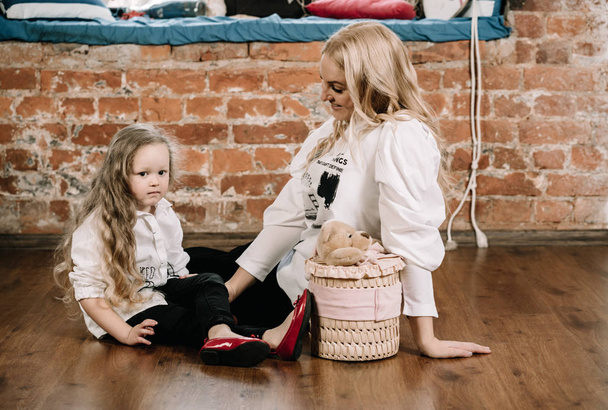 bella madre bionda e la sua piccola figlia caucasica seduta sul pavimento con grande regalo di scatola e felice insieme
 - Foto, immagini