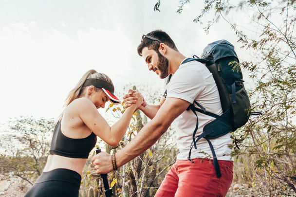 Male hiker helping his girlfriend uphill in the countryside. You - Foto, Imagem