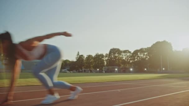 Beautiful Fitness Woman in Light Blue Athletic Top and Leggings is Starting a Sprint Run in an Outdoor Stadium. She is Running on a Warm Summer Day. Athlete Doing Her Sports Practice. Tracking Shot. - Materiał filmowy, wideo