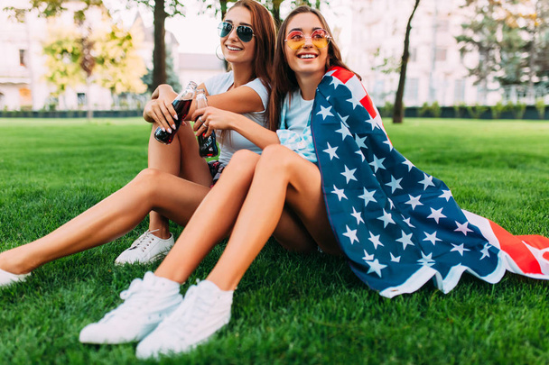 Two attractive young girls in sunglasses sitting in the Park on  - Photo, image