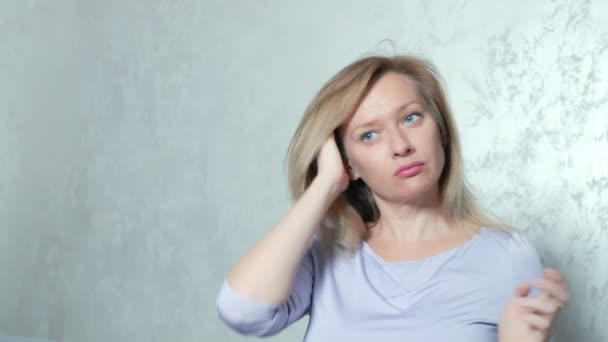 alopecia, baldness. a blonde woman straightens her hair and a tuft of hair remains in her hands. copy space - Footage, Video