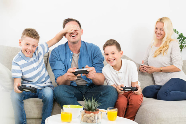 Szczęśliwy młody rodzina gra Videogame w TV. - Zdjęcie, obraz