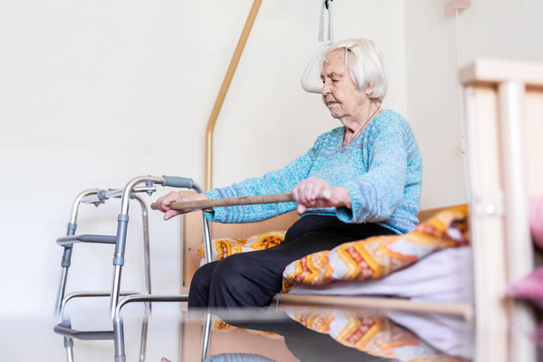 Літня 96-річна жінка займається з палицею, сидячи на її поганому
. - Фото, зображення