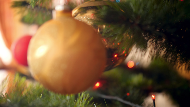 Renkli çelenk, ışık ve topları ile süslenmiş Noel ağacı arasında yavaş yavaş hareket eden kamera 4k video. Kış tatilleriniz ve kutlamalarınız için mükemmel çekim - Video, Çekim