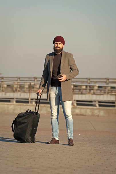 Carry travel bag. Business trip. Man bearded hipster travel with big luggage bag on wheels. Let travel begin. Traveler with suitcase arrive to airport railway station. Hipster ready enjoy travel - Photo, Image