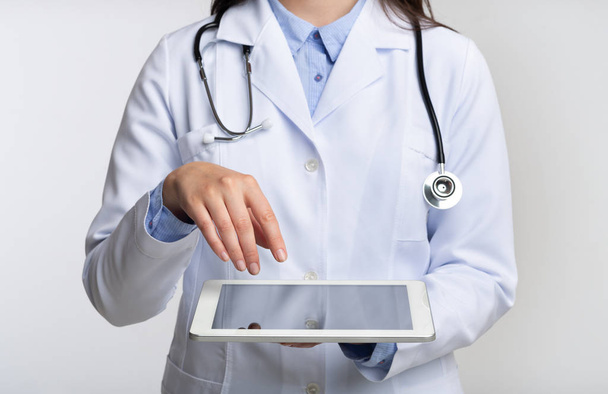 Μη αναγνωρίσιμος γιατρός χρησιμοποιώντας tablet Computer, λευκό φόντο, περικομμένο - Φωτογραφία, εικόνα