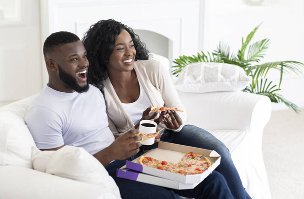 Αφρικάνικο ζευγάρι που τρώει πίτσα και πίνει καφέ στο σπίτι - Φωτογραφία, εικόνα