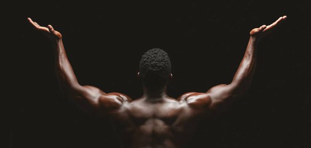 Rear view of african bodybuilder raising his palms up - Photo, Image