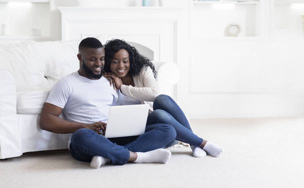 Young black couple using laptop at home planning summer vacation - Foto, Bild