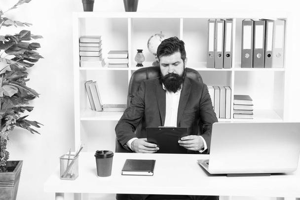 Check list. Man bearded hipster boss sit in leather armchair office interior. Boss at workplace. Manager formal clothing corporate style working. Business people concept. Busy boss in office - Foto, afbeelding