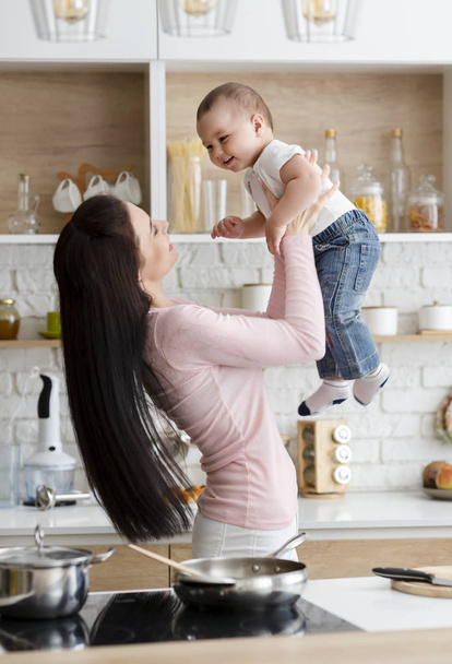 Maminka zdvihala svého syna na vzduchu, společně vaří oběd - Fotografie, Obrázek