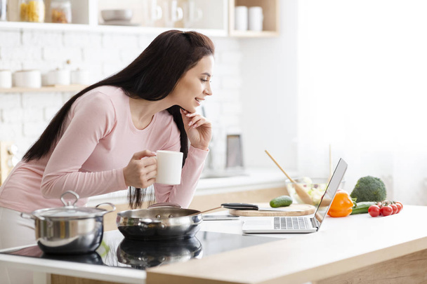 Millennial Business vrouw werkt op een laptop in de keuken - Foto, afbeelding