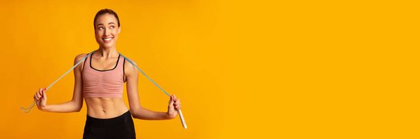 Χαμογελαστή γυναίκα κρατώντας σχοινί άλμα θέτοντας σε στούντιο, Πανόραμα - Φωτογραφία, εικόνα
